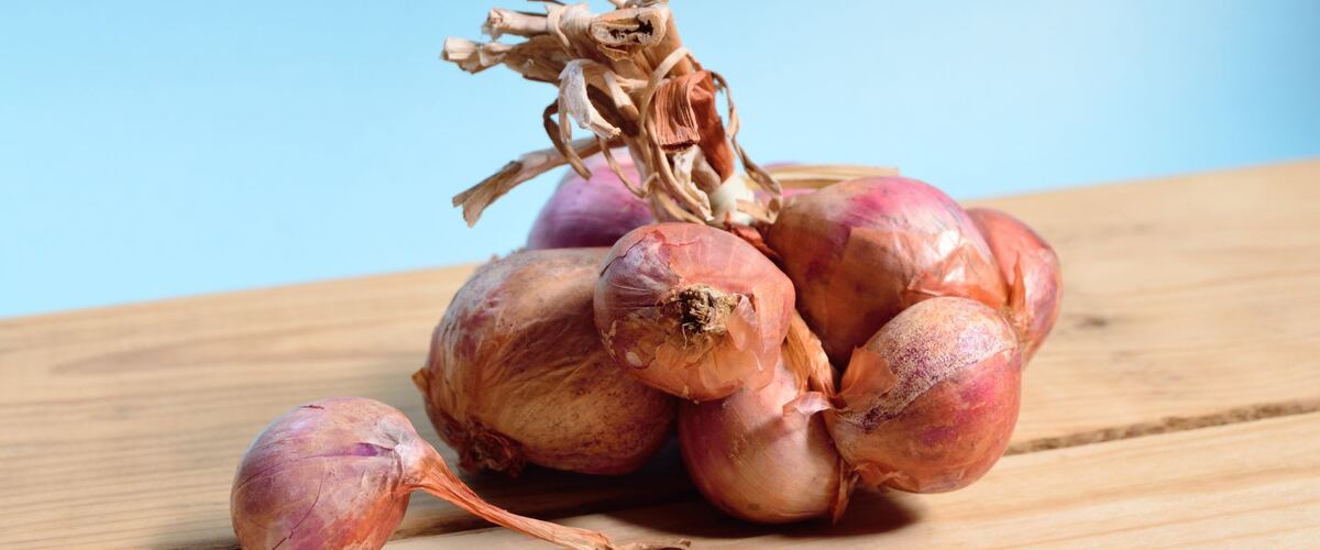 A cluster of shallots on a wooden table